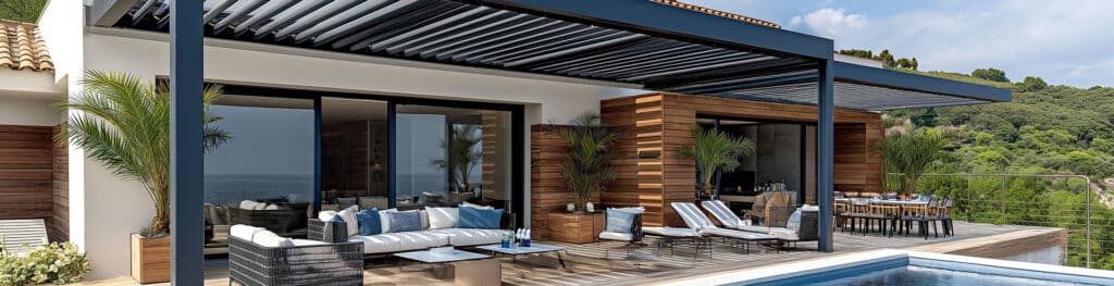 Grande terrasse moderne avec pergola bioclimatique, salon extérieur, coin repas, piscine et vue sur la mer et collines verdoyantes.